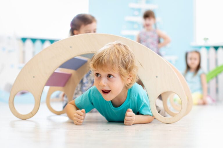 A smiling toddler riding a NEWTRONX Toddler Tricycle, excitedly exploring the outdoors while developing essential motor skills and enjoying physical activity.
