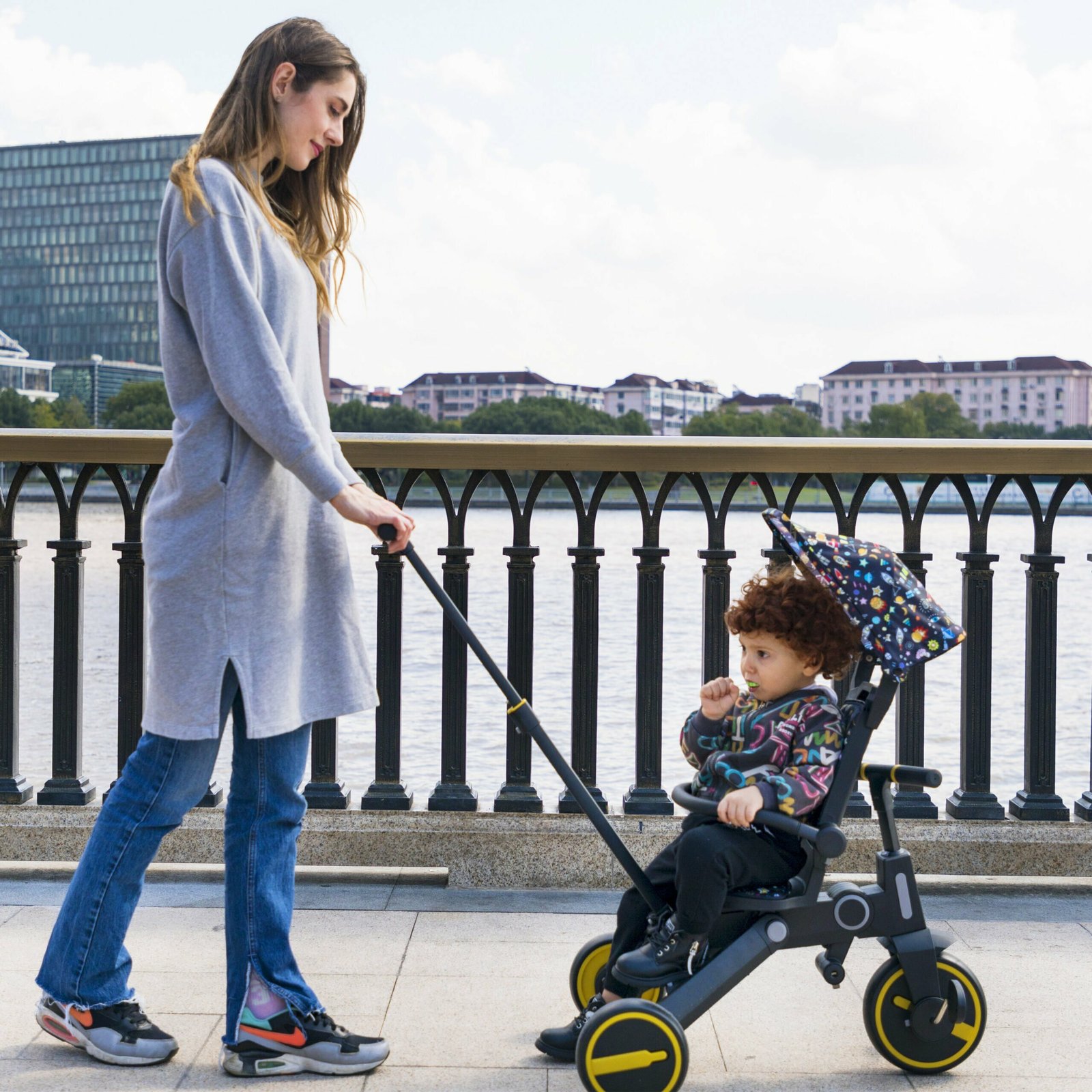Parent pushing a toddler on a Newtronx foldable tricycle